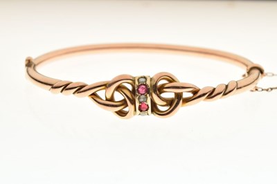 Lot 47 - Yellow metal (9ct 'rose gold'), ruby and tinted split pearl snap bangle