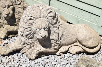 Lot 827 - Pair of composite stone garden lions in recumbent posture