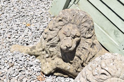 Lot 827 - Pair of composite stone garden lions in recumbent posture