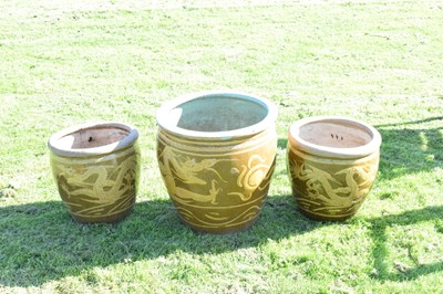 Lot 690 - Group of three Chinese brown glazed stoneware urns with dragon decoration