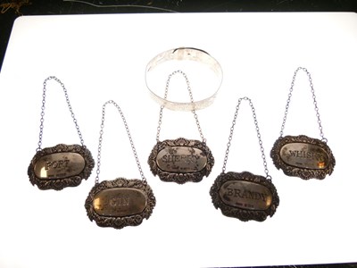 Lot 94 - Set of five silver decanter labels and a white metal bangle