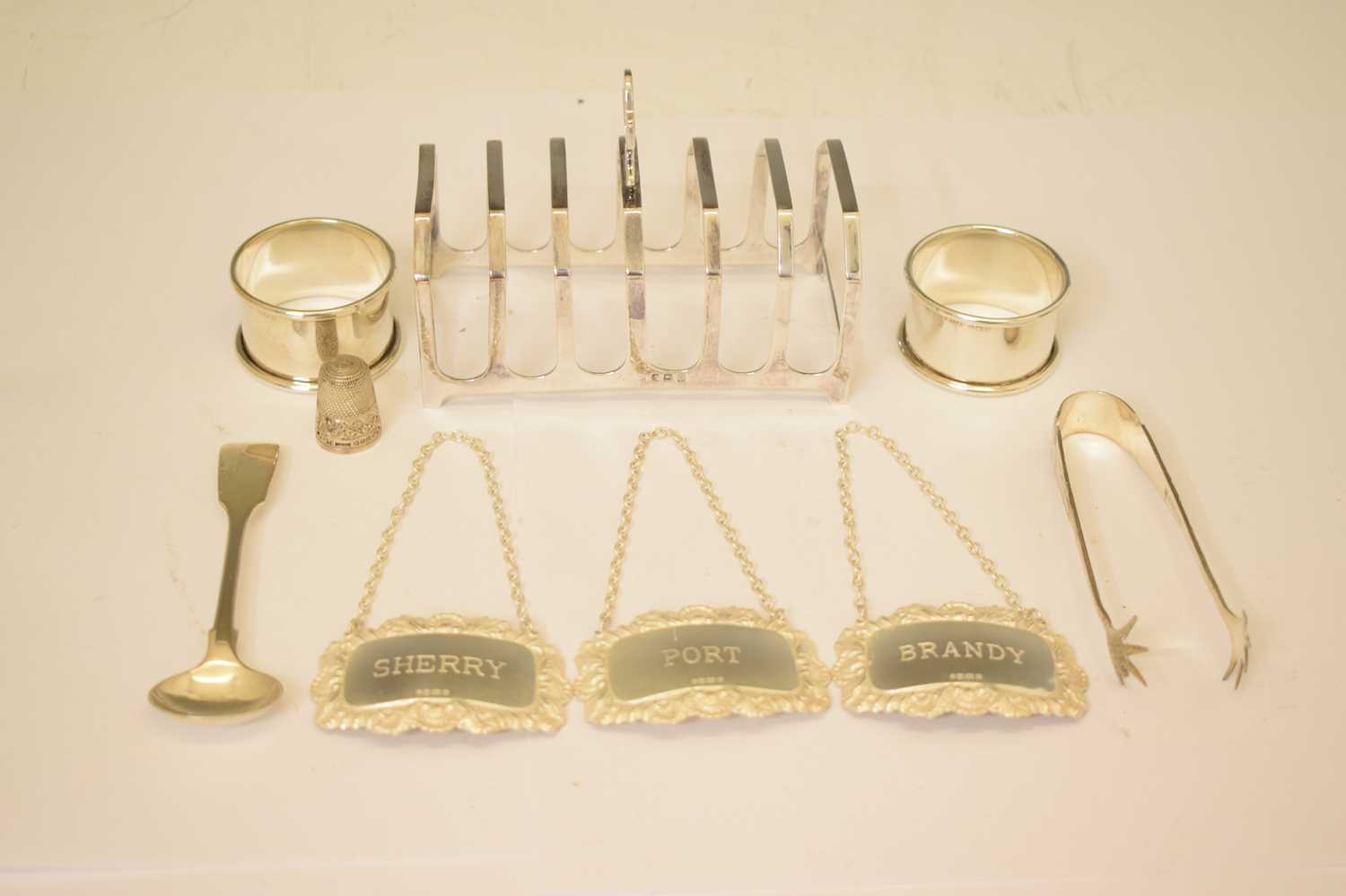 Lot 161 - George V silver toast rack, a set of three Elizabeth II silver decanter labels, etc